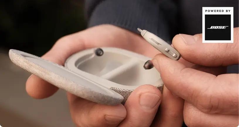 Hands holding the Lexie B1 hearing aids Powered by Bose and case.