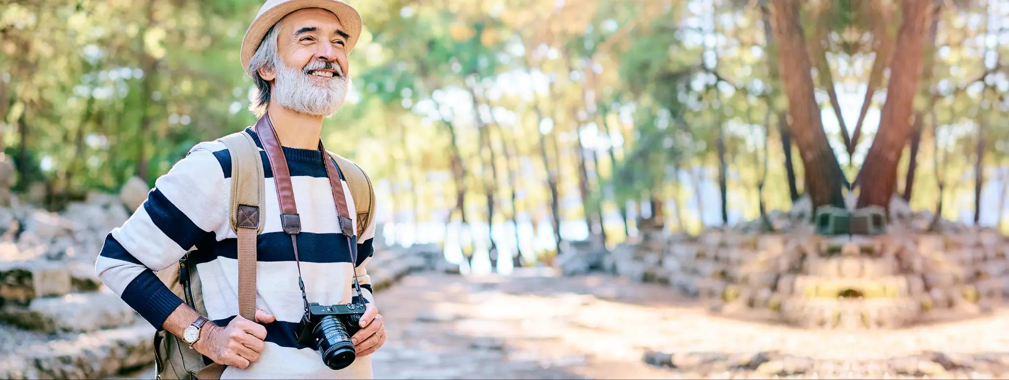 Senior man on a hike in the woods with a hat on his head