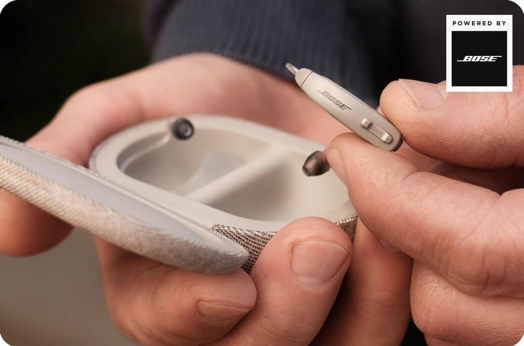 Hands holding the Lexie B1 hearing aids Powered by Bose and case.