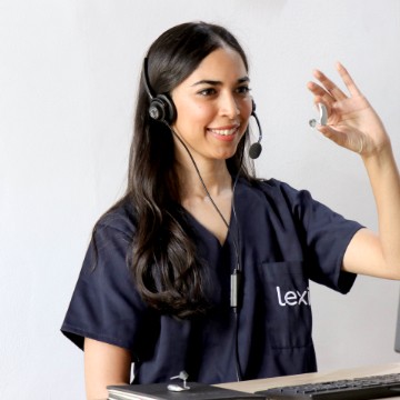 Lexie Expert wearing a headset and holding up a Lexie hearing aid.