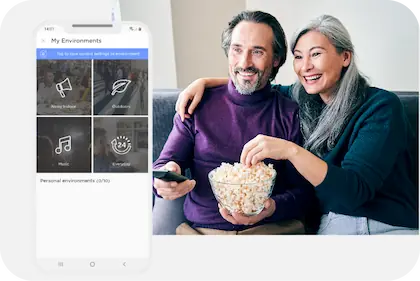 A screenshot of the Lexie Hearing App's environmental selection page. To the right is a man, in suite, looking at her phone.