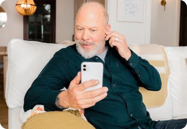 A man on a couch, on his phone, using the Lexie App.
